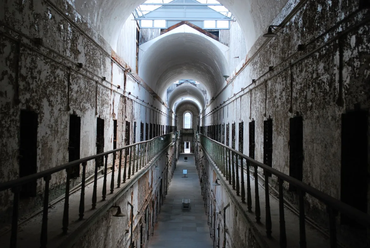 Cellule de prison du XIXe siècle avec mobilier spartiate et fenêtre barricadée