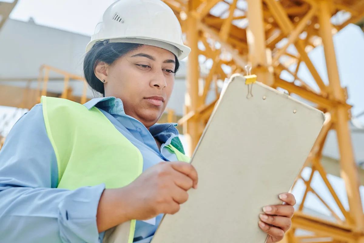 Auditeur en visite de site effectuant des relevés terrain et notant les données dans un formulaire