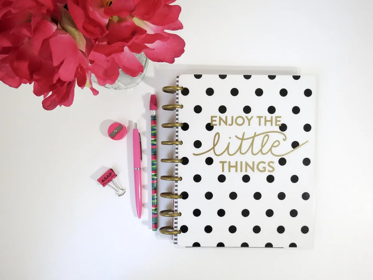 Main écrivant dans un journal de décisions sur un bureau ensoleillé