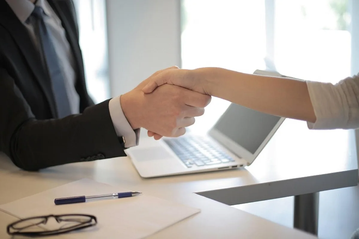 Deux personnes signent un accord professionnel à un bureau, symbole d'engagement contractuel.